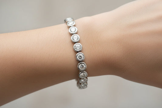 Close-up of a sleek bezel-set diamond tennis bracelet on a wrist, highlighting modern minimalism and smooth metal rims that encircle each diamond.