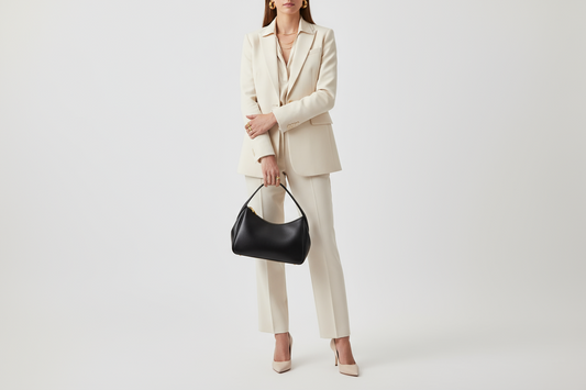 Woman holding a leather handbag and wearing gold jewelry with matching heels, showcasing perfect coordination between jewelry, bags, and shoes.