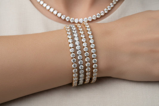 A close-up, luxurious shot of layered tennis bracelets and a tennis necklace in mixed metals—white gold, yellow gold, and rose gold—styled together on a wrist or display. Diamonds sparkle evenly, showing how the metals blend harmoniously.