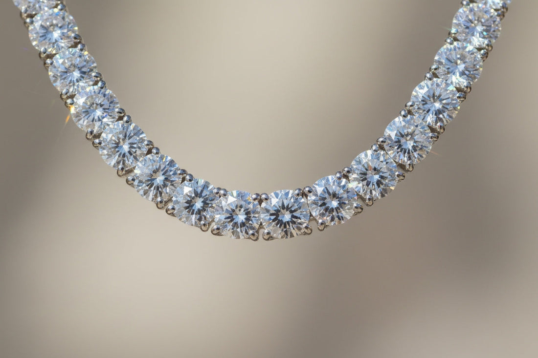 A close-up of a high-quality tennis necklace with perfectly cut diamonds reflecting sunlight, showing brilliance, fire, and scintillation. The diamonds glisten with rainbow colors, placed on a soft neutral background to emphasize sparkle and elegance.