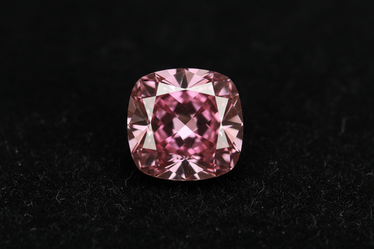 Close-up of a vivid pink diamond on black velvet showcasing its intense color and rarity.